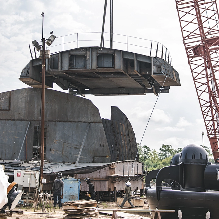 crane lifting part of boat. Man with tagline