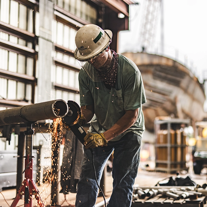 man cutting pipe with angle grinder