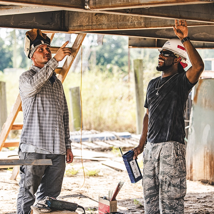 men pointing up at iron and working